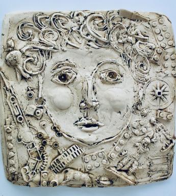 Plaster cast of a face with curly hair surrounded by miscellaneous objects
