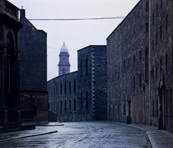 Photograph of a stone-building-lined street with a church spire in distance.