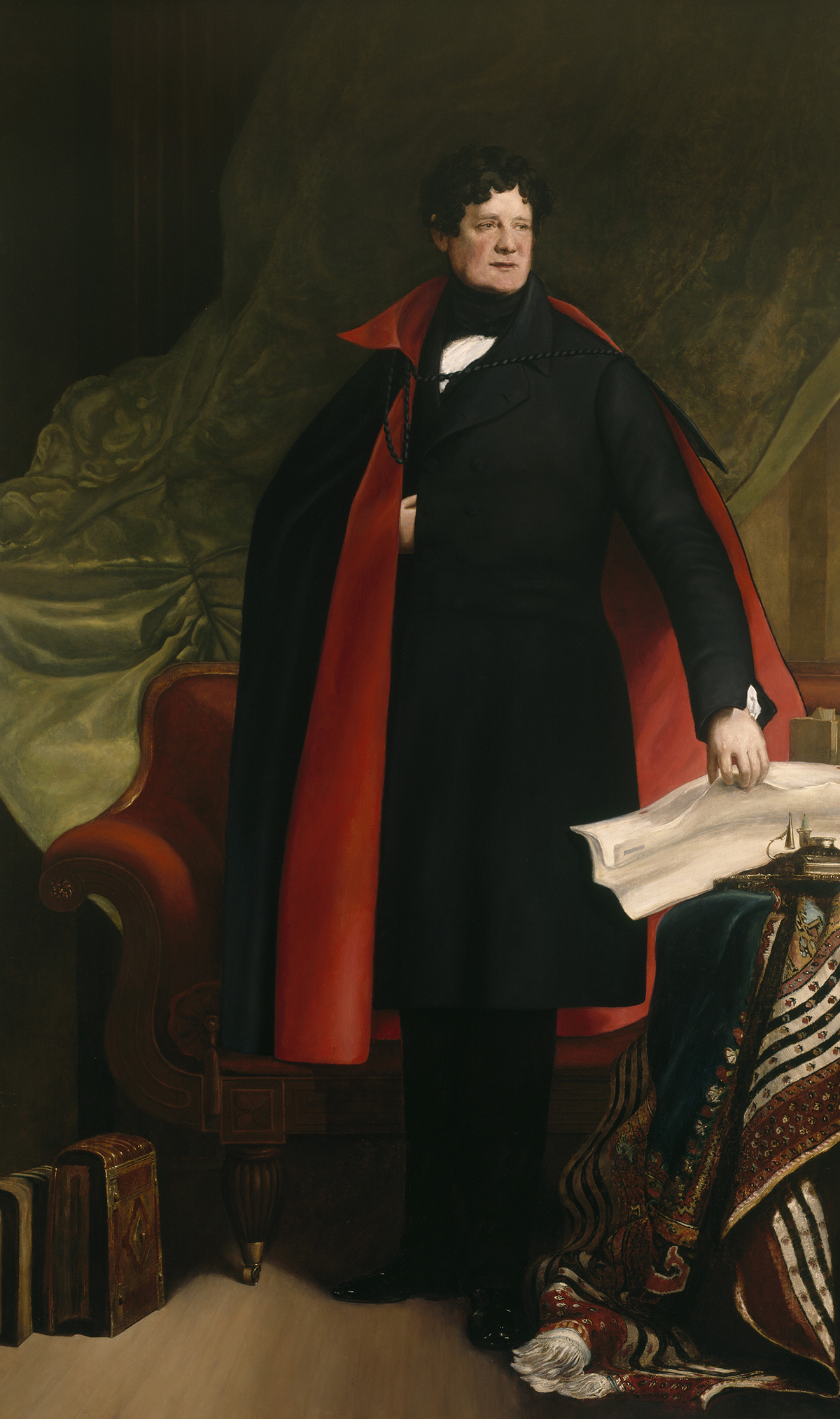 A full-length portrait. Daniel O'Connell wears a red-lined cloak, with one hand on his breast.