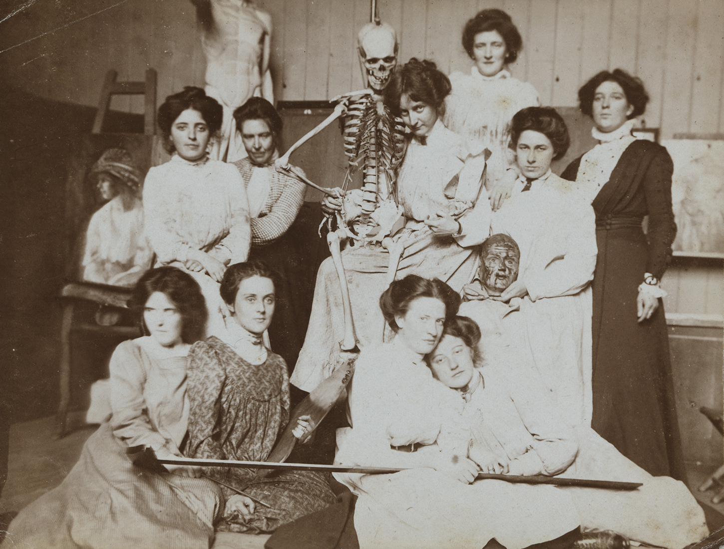 Vintage black and white photo of women posing with a medical skeleton model