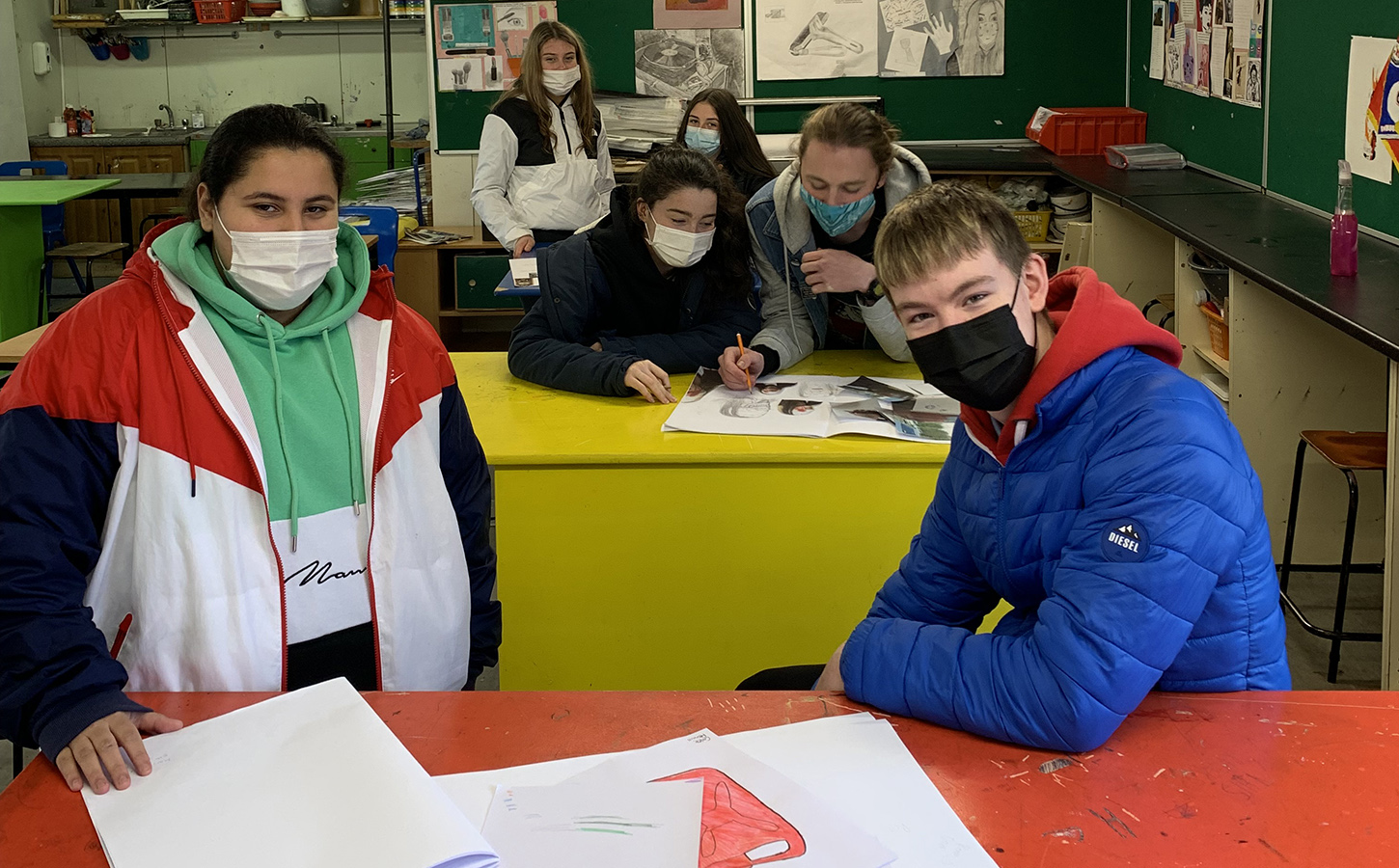 Photo of a group of young people wearing face coverings in an art classroom