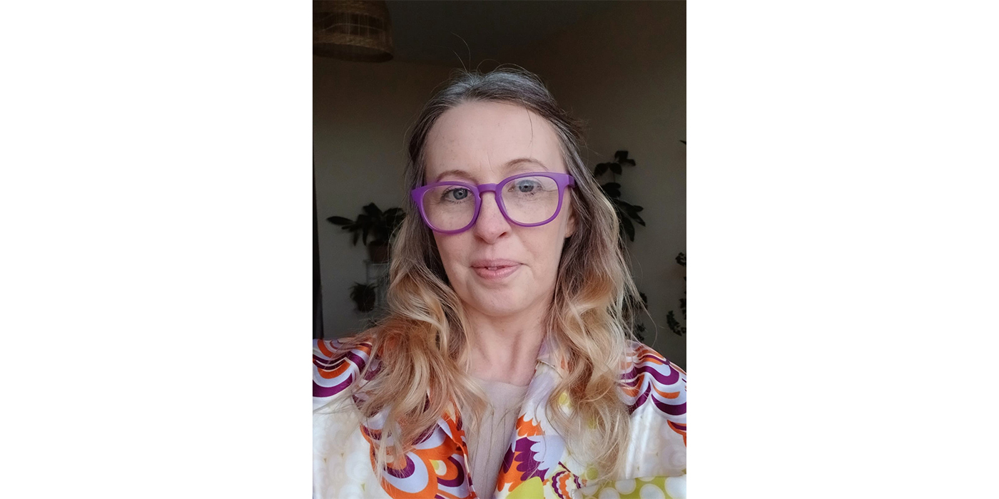 Headshot of a woman with blond curly hair and glasses