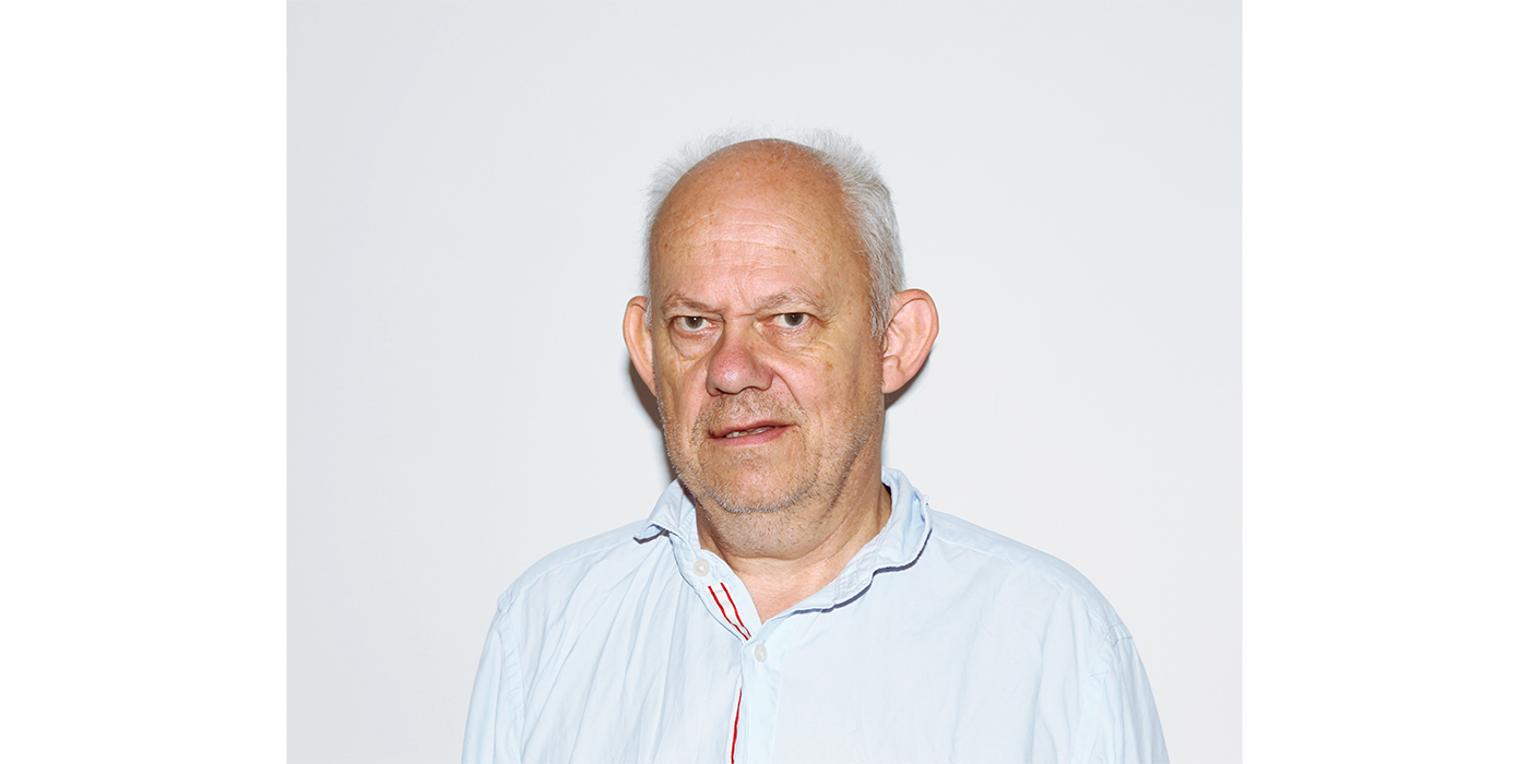 Headshot of a white man with short white hair, wearing a light blue shirt