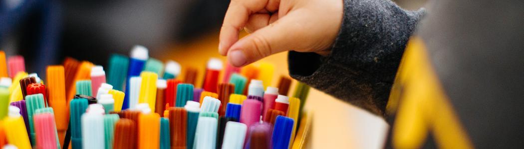 Photo of a child's hand picking a felt tip pen out of a box.