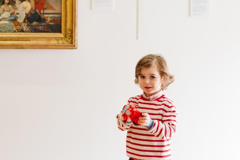 A child standing in front of a gold-framed painting in the Gallery