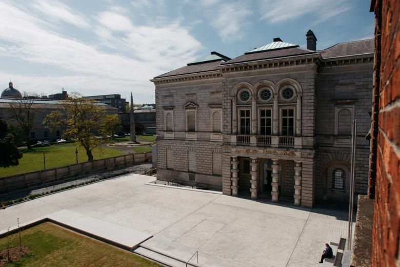 A colour photograph showing the stone facade of the Gallery's historic wing taken from a height. The sky is blue and streaked with white clouds. 