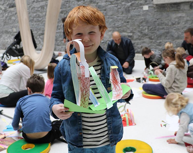 A young boy holds up the artwork he created a drop-in family workshop in the National Gallery of Ireland.