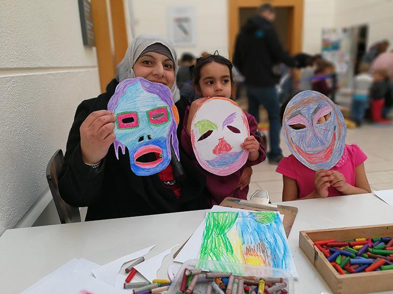 A family hold up the masks that they created at a drop-in family workshop at the National Gallery of Ireland.