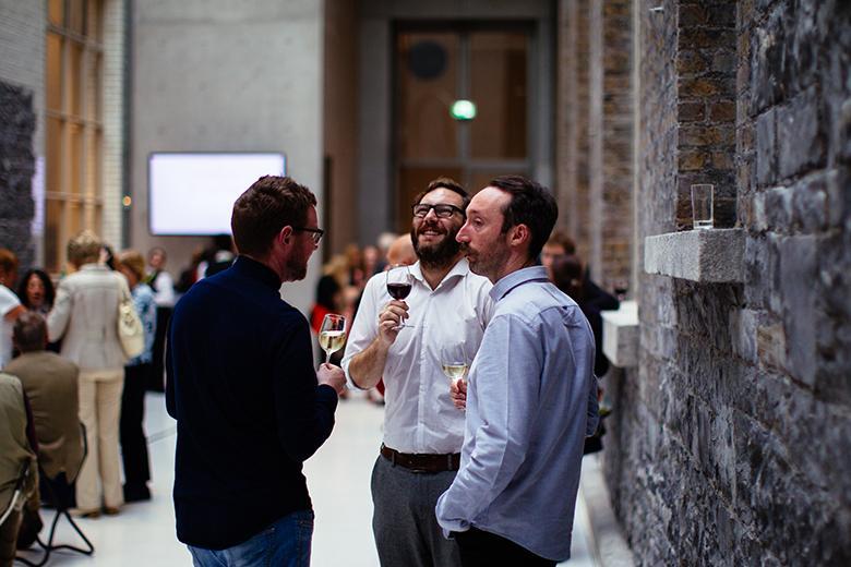Three men drinking wine at an event
