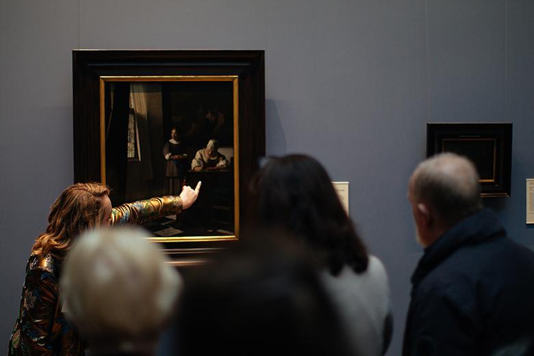 Tour guide speaking to a group of visitors in front of Vermeer's painting