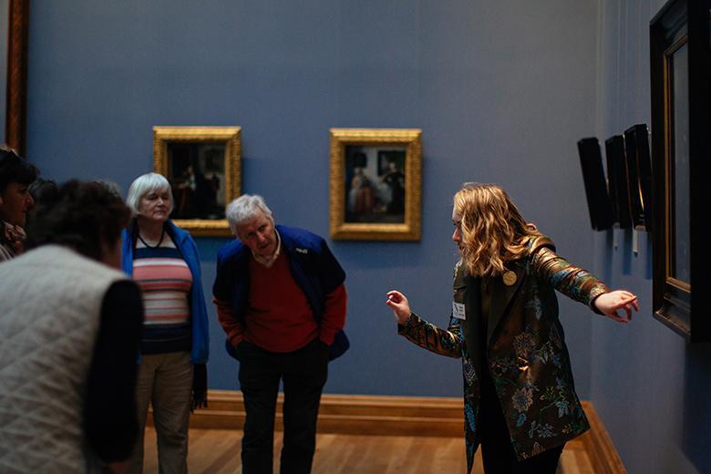 Tour guide speaking to a group of Gallery visitors in front of a painting