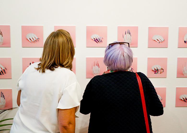 Photo of two women looking at photographs of nail art