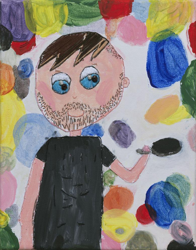 A blue eyed man in a black t-shirt holds a frying pan aloft, as if flipping pancakes. He is surrounded by discs of different colours, so that we can't tell which are the pancakes.