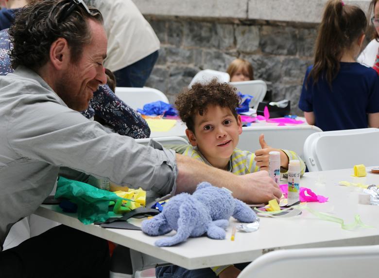 Photo of a boy and his father making art at a table.