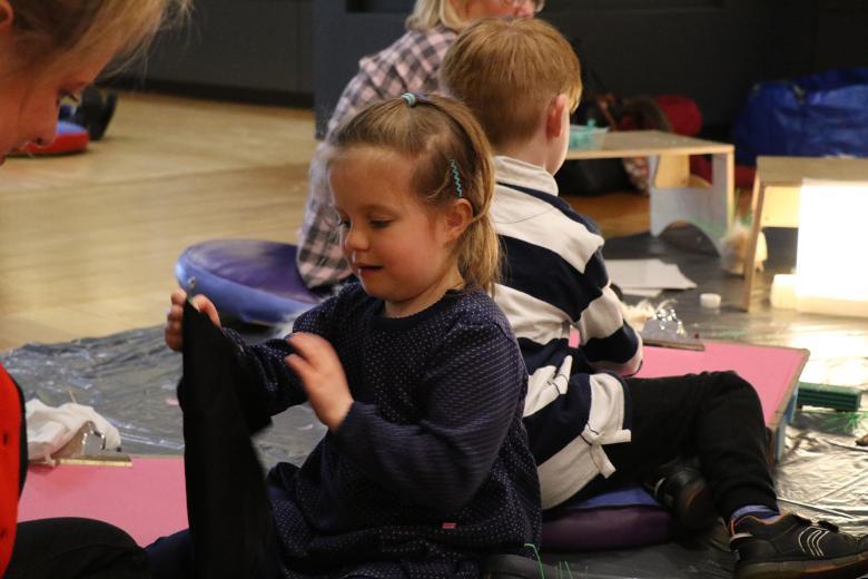 Photo of a child sitting on the floor taking part in an art workshop.