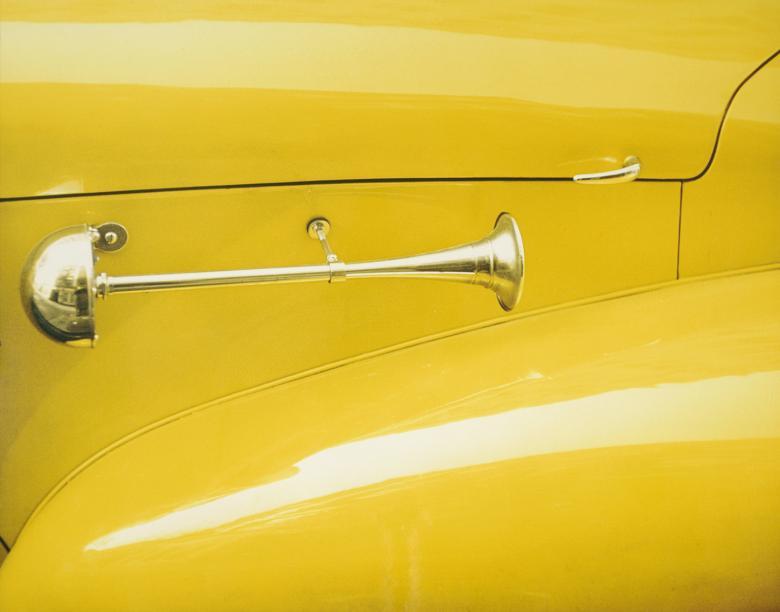 Closely cropped colour photo of a yellow car