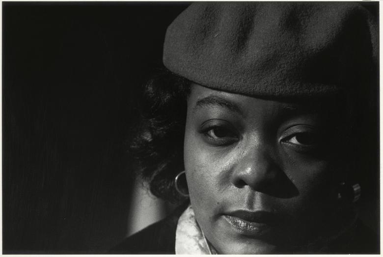 Black and white closely cropped photographic portrait of a woman wearing a hat
