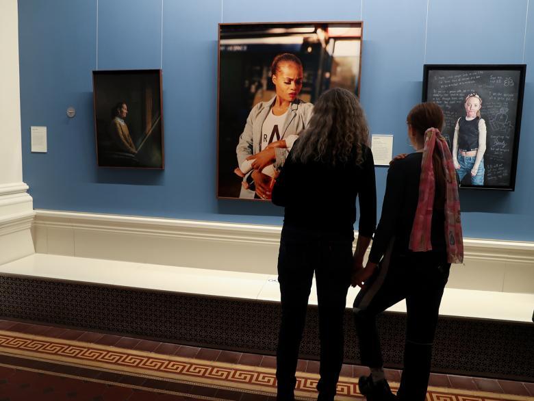 Photo of two women looking at three portraits in an exhibition