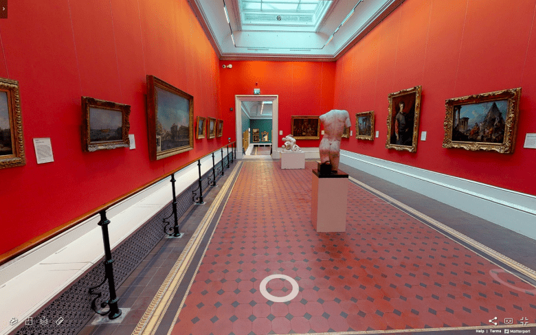 A view of a vibrant red gallery lined with paintings. On the tiled floor stand some sculptures