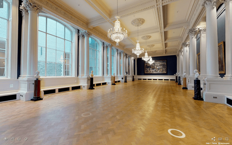 A long Gallery with chandeliers, polished wooden floors, and large windows at one side.