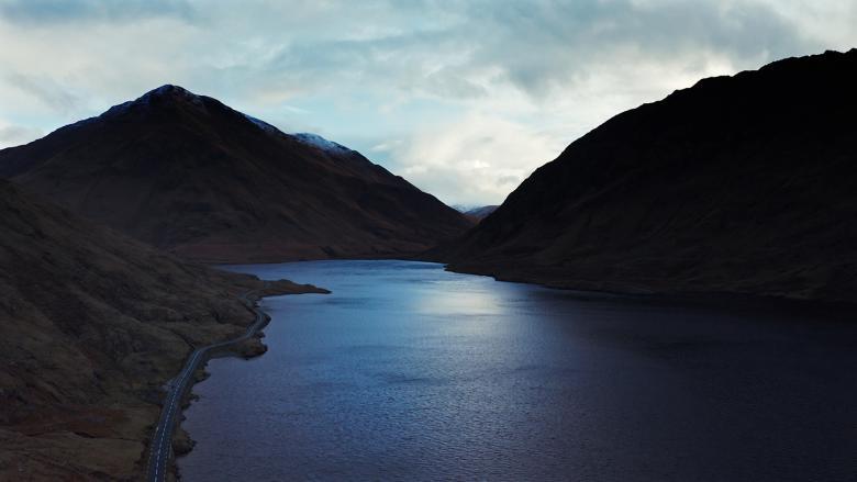 A still from a documentary film, showing a lake surrounded by mountains