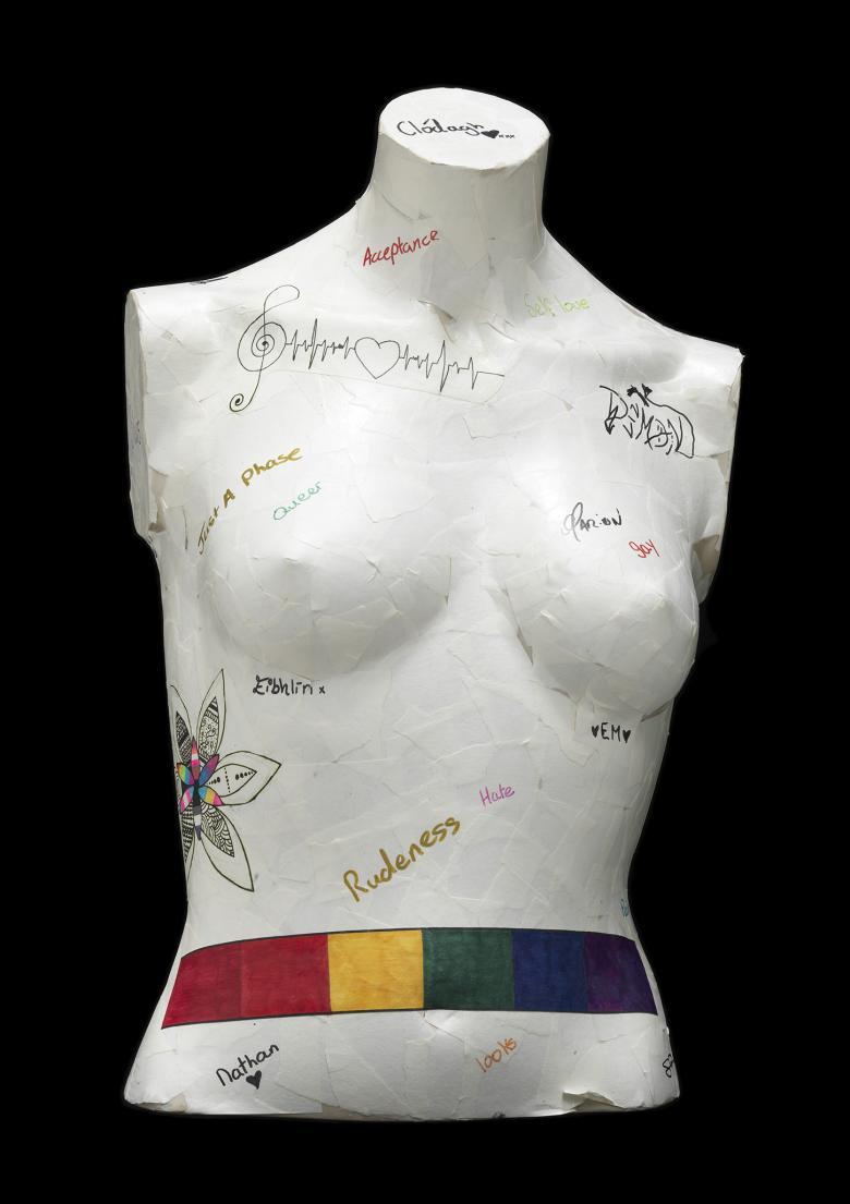 White mannequin bust with text graffiti and a rainbow coloured belt