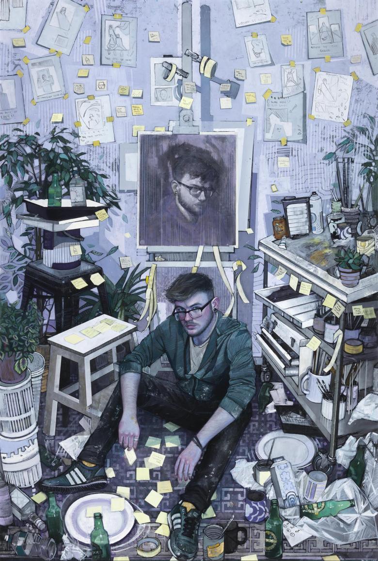 View of an artist's studio with a man wearing glasses seated on the floor in front of an easel with a self-portrait. Artist materials and sketches and plants surround him.