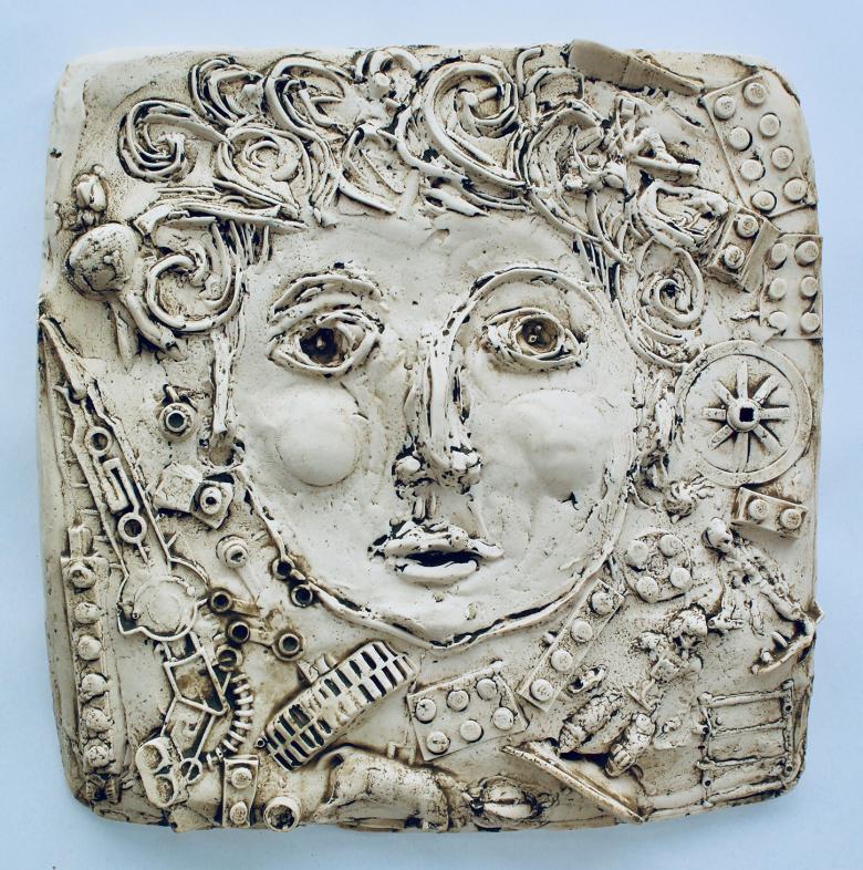 Plaster cast of a face with curly hair surrounded by miscellaneous objects