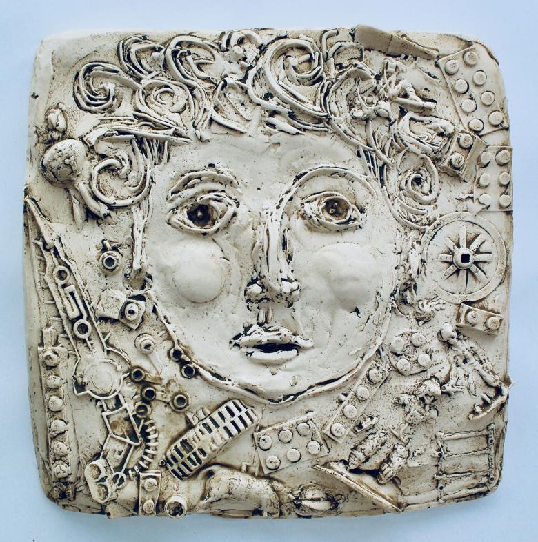 Plaster cast of a face with curly hair surrounded by miscellaneous objects