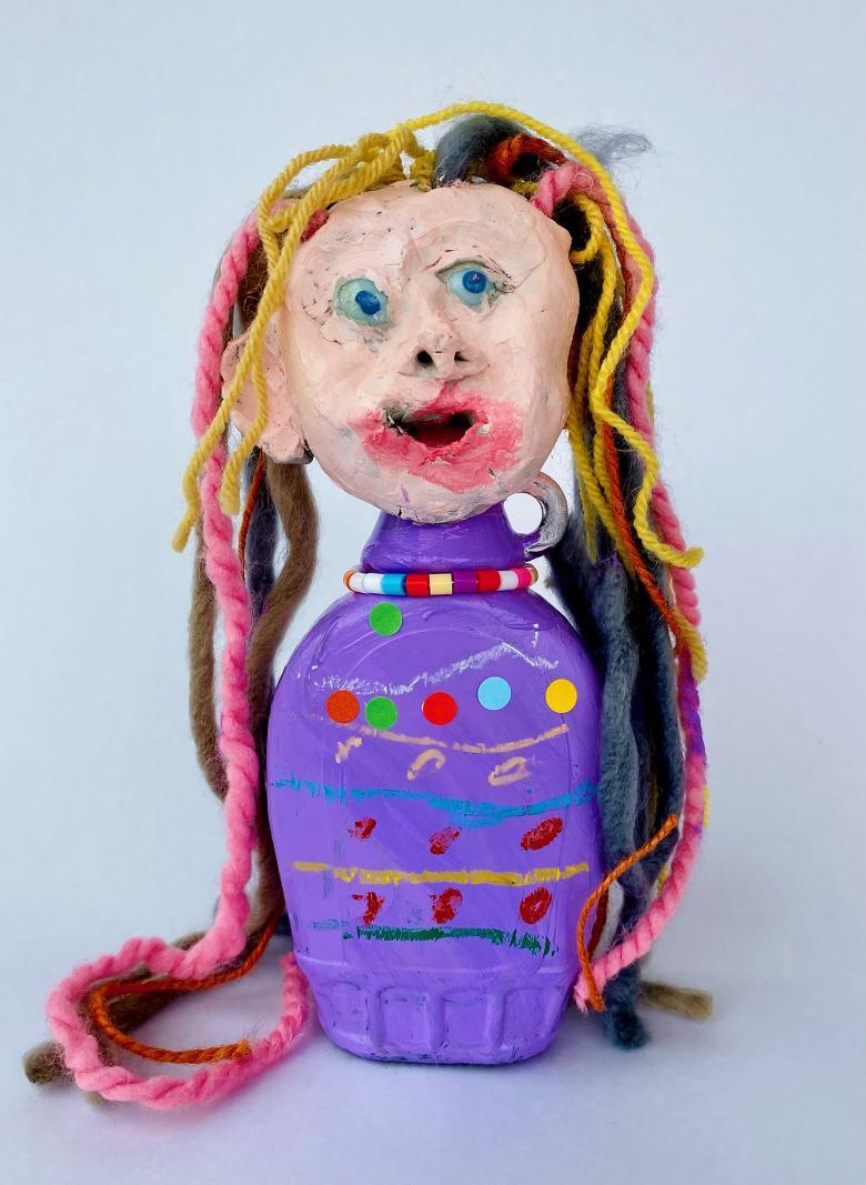 Sculpture of a female head with blue eyes and multi-coloured hair on a purple stand with coloured beads