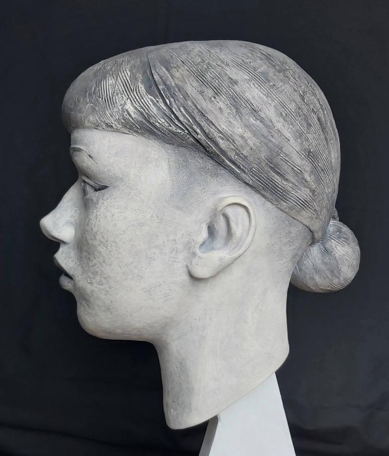 Black and white photograph of a clay sculpture of a female head