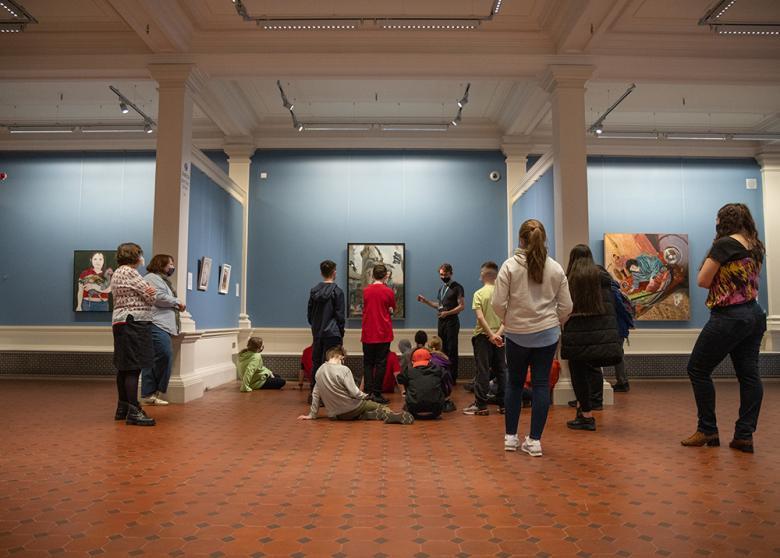 Photograph of a group of children standing in a blue room looking at a painting