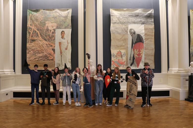 A group of TY work experience students in costume standing in front of Hughie O'Donoghue's art installation 'Original Sins'