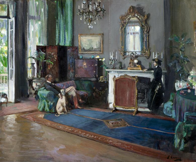 An oil painting of a high-ceilinged drawing room furnished with free curtains, a large blue rug, a chandelier, mirrors, paintings and plants. A woman in a dark dress and hat stands at the fireplace. She is looking towards a man seated of a sofa, with his hand on a large greyhound.