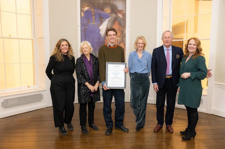 Photograph of a group of six adults, on holding a framed certificate