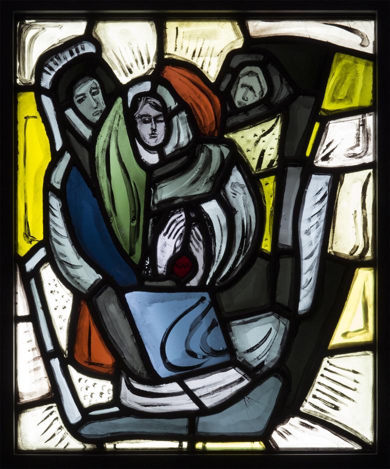 A piece of stained glass featuring three figures, with colours of white, yellow, red, green and blue