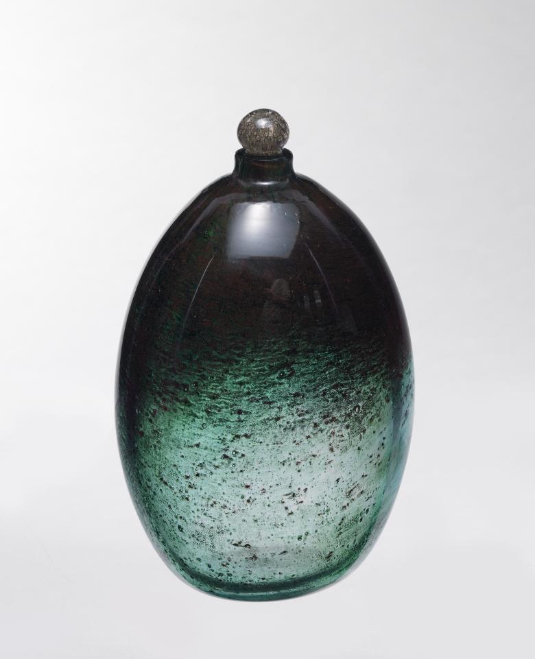 A rounded glass flagon in green and black glass with a small stopper.