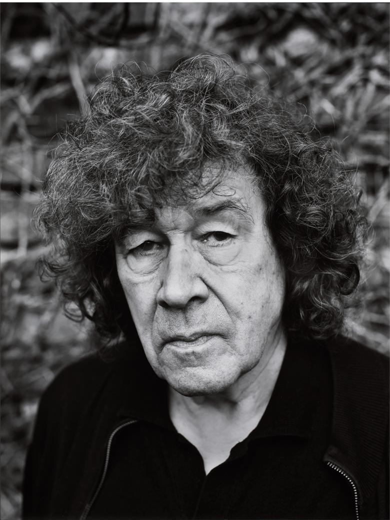 Black and white portrait of a man with dark curly hair and a black jacket.