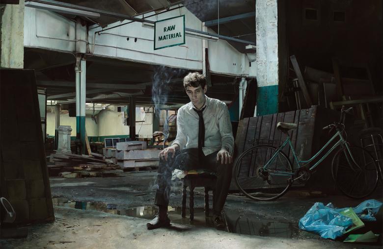 A painting of a young man, sitting on a chair in a dark abandoned warehouse, surrounded by rubbish.