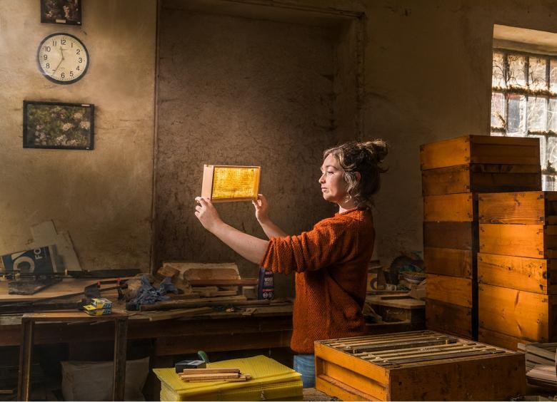 A woman holds a honeycomb up to the light.