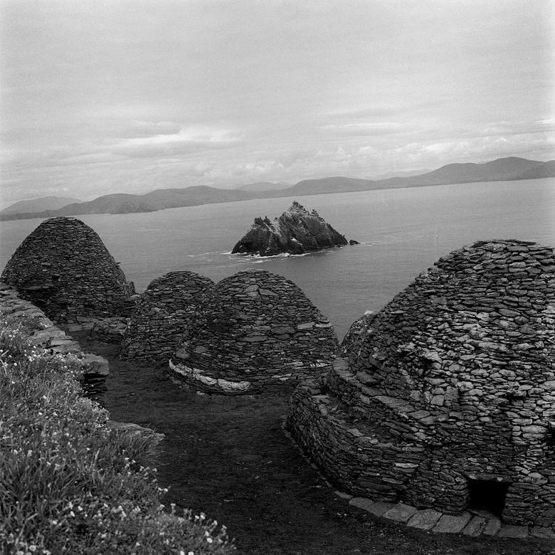 Black and white photograph of the beehive shaped stone huts on top of Skellig Michael