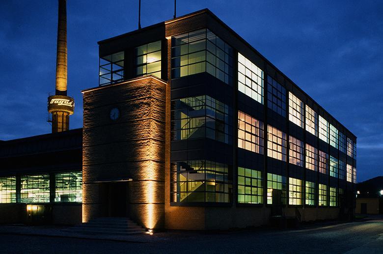 Nighttime photo of a Bauhaus building with lights inside illuminating the windows.