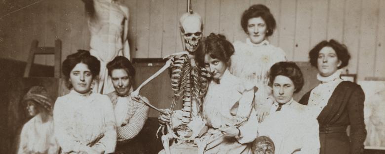 Vintage black and white photo of women posing with a medical skeleton model