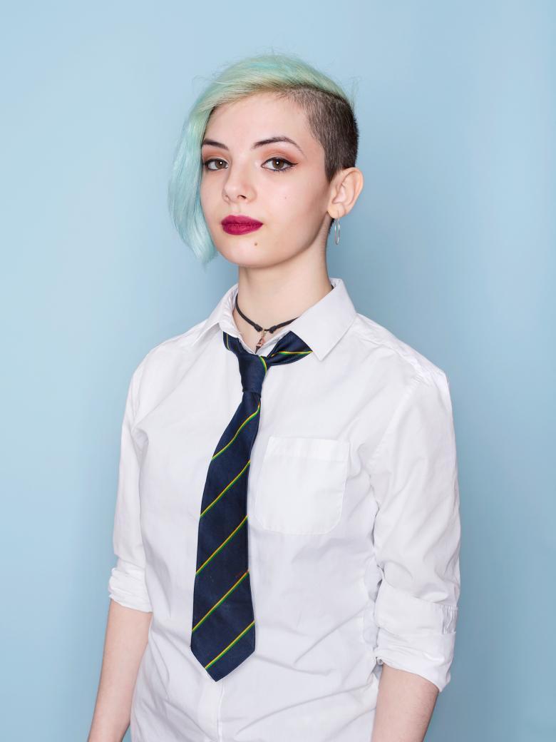 Colour photograph portrait by artist Mandy O'Neill showing teenage girl in school uniform against a pale blue background.