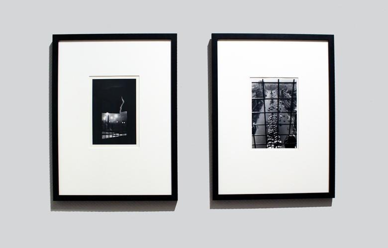 Two black and white photographs, framed and mounted, hanging side by side on a grey wall. 