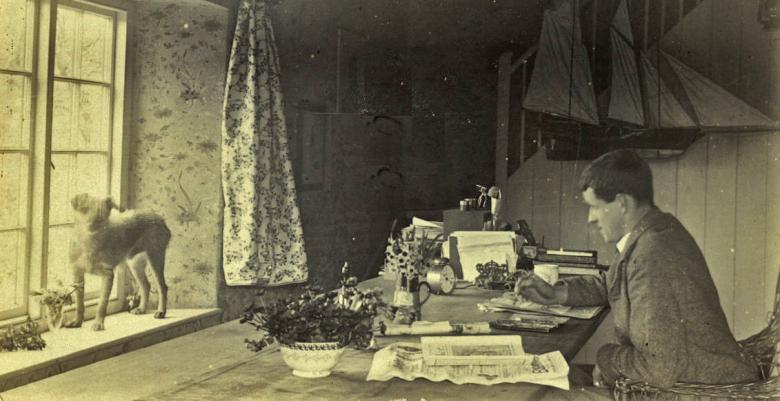 Jack B Yeats sits at his desk working - in front of him, standing on the window sill and looking directly at the camera is his dog HooliganGallery of Ireland's Yeats Archives
