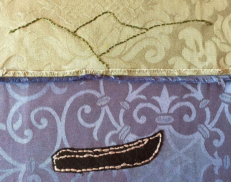 Photo of textile art showing a currach and mountains embroidered on cloth.