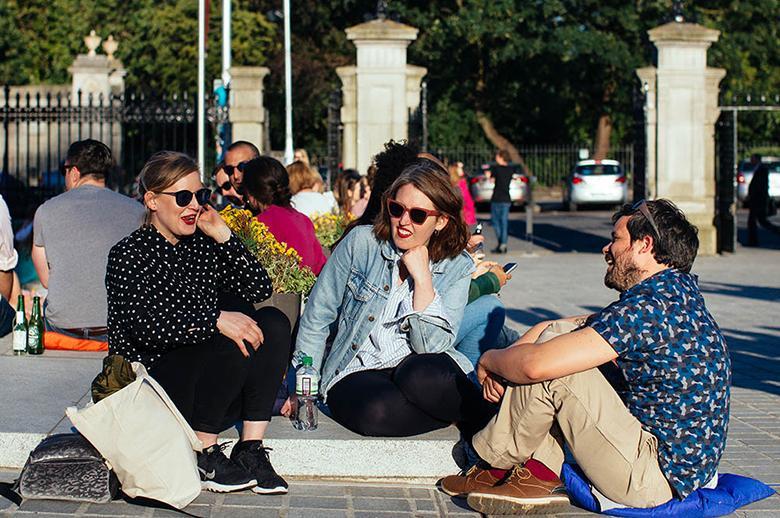 A group of three people sitting on steps and talking