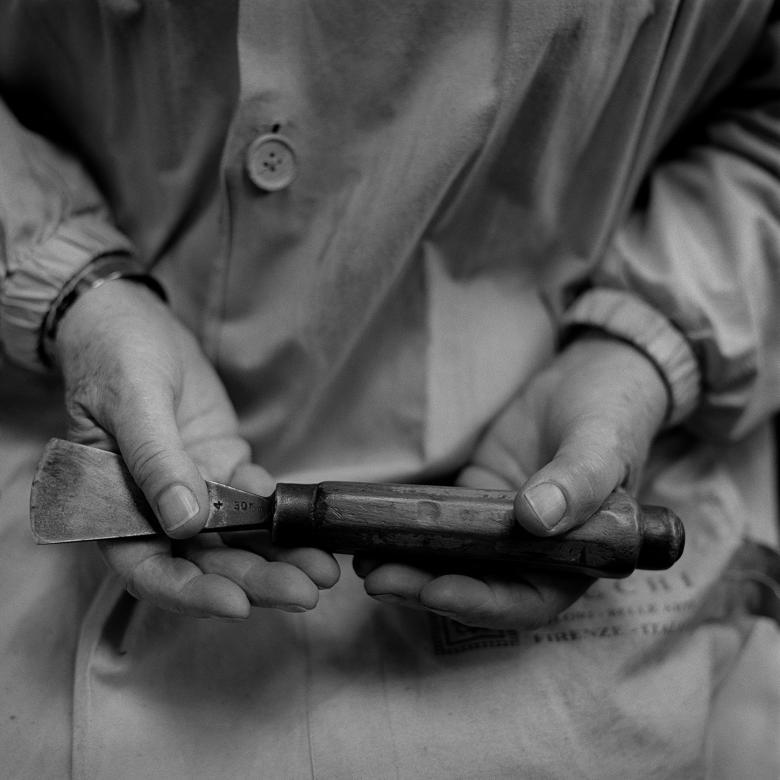 A black and white photograph of artist Imogen Stuart's hands holding a sculptors' chisel.