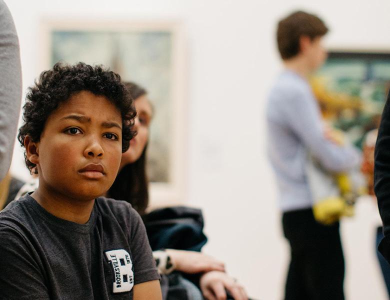 A child seated in the Gallery and listening to a tour guide.